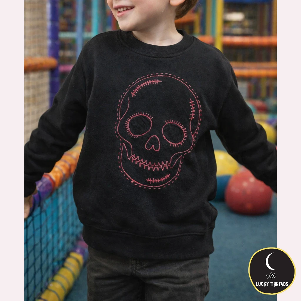creepy cute sweater in black pink threads by lukcy threads. kids wearing black sweater with a pink skull